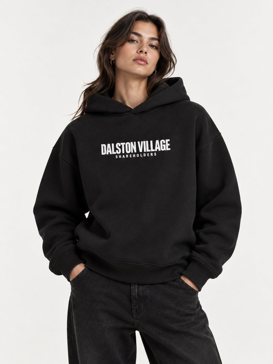 AI-generated studio styling visual of a female model wearing the black Dalston Village Shareholders heavyweight hoodie with white chest branding. Not a physical fit photograph.